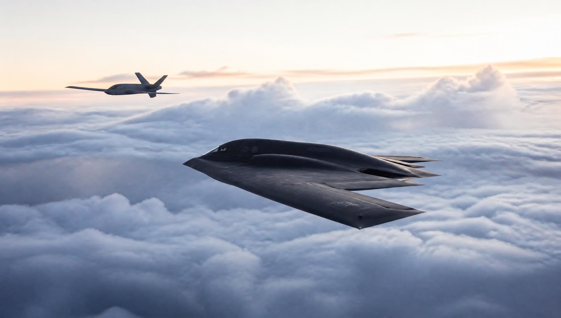 Stealth bomber and unmanned aerial vehicle above a cloud layer at dawn